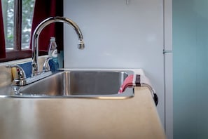 A kitchen with a stainless steel sink, a faucet, and a window with curtains.