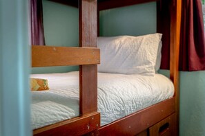A bunk bed with a wooden frame, white bedding, and a single pillow.