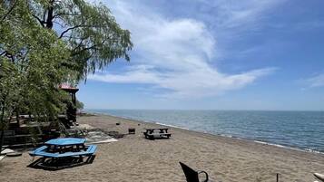 Une plage avec une terrasse en bois, une table bleue et un banc.