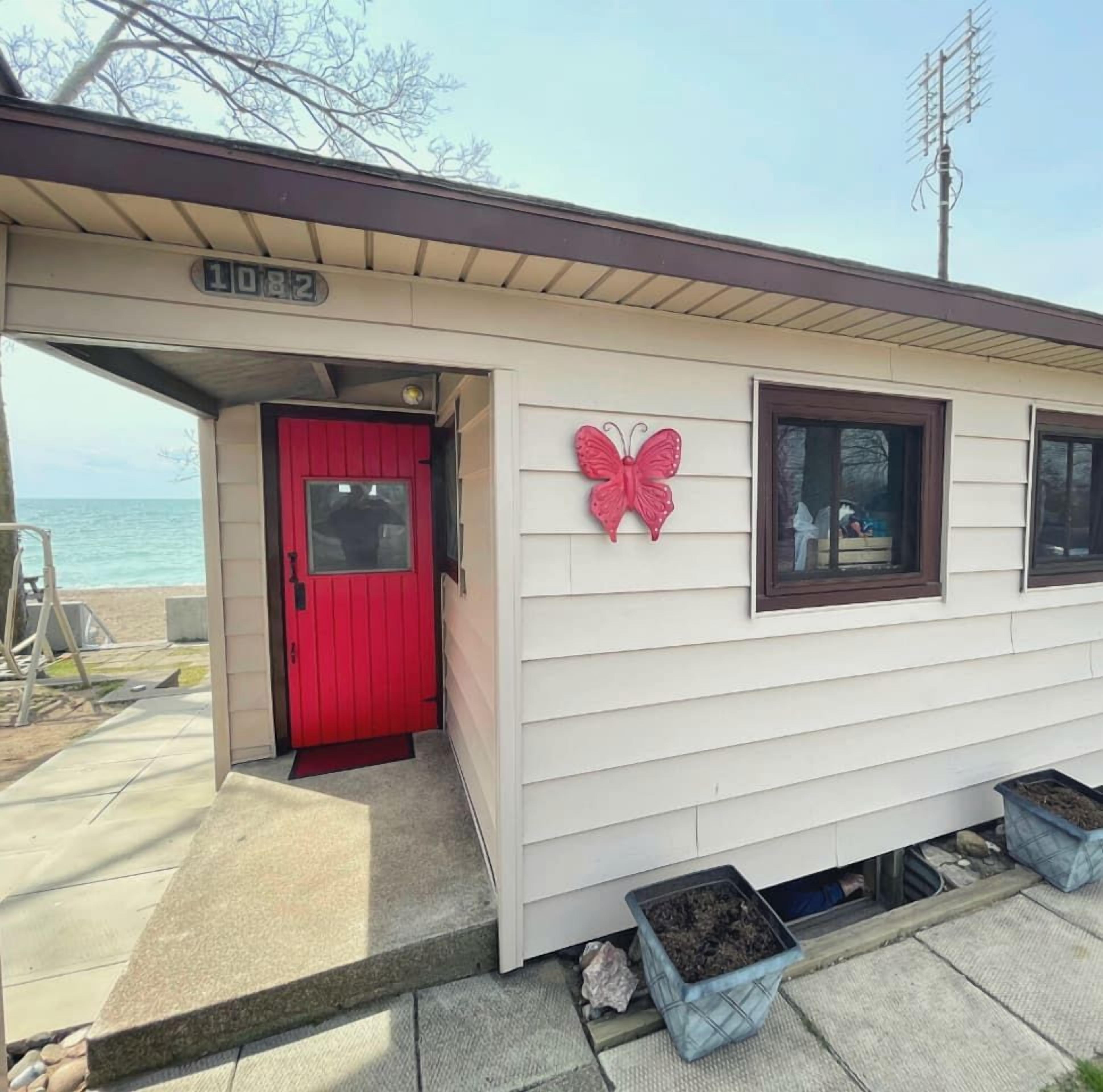 A small building with a red door, a butterfly decoration, and a number '1092' on the roof.