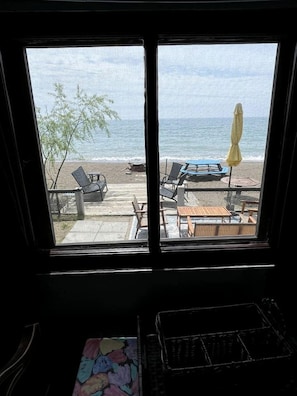A room with a large window overlooking a beach with lounge chairs and a yellow umbrella. - Cozy Lake Tiny House Incredible to Create New Memories in Ontario (Leamington)