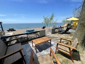Une terrasse au bord de la plage, avec des sièges extérieurs, une table et une vue sur l’océan.