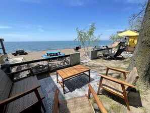 Une terrasse au bord de la plage, avec des sièges extérieurs, une table et une vue sur l’océan.