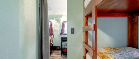 A bunk bed room with a wooden headboard, a small table, and a chair.