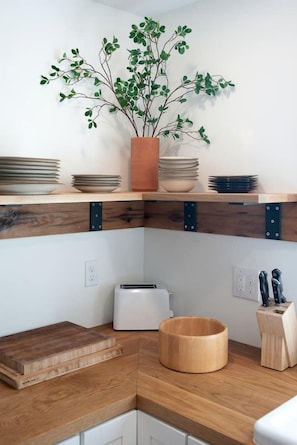 Eine Küche mit Holzausziehtischen, einem Toaster, einer Holzkolle und einem Blumentopf auf einem Regal.