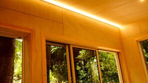 A room with wooden paneling, large windows, and a view of greenery outside.