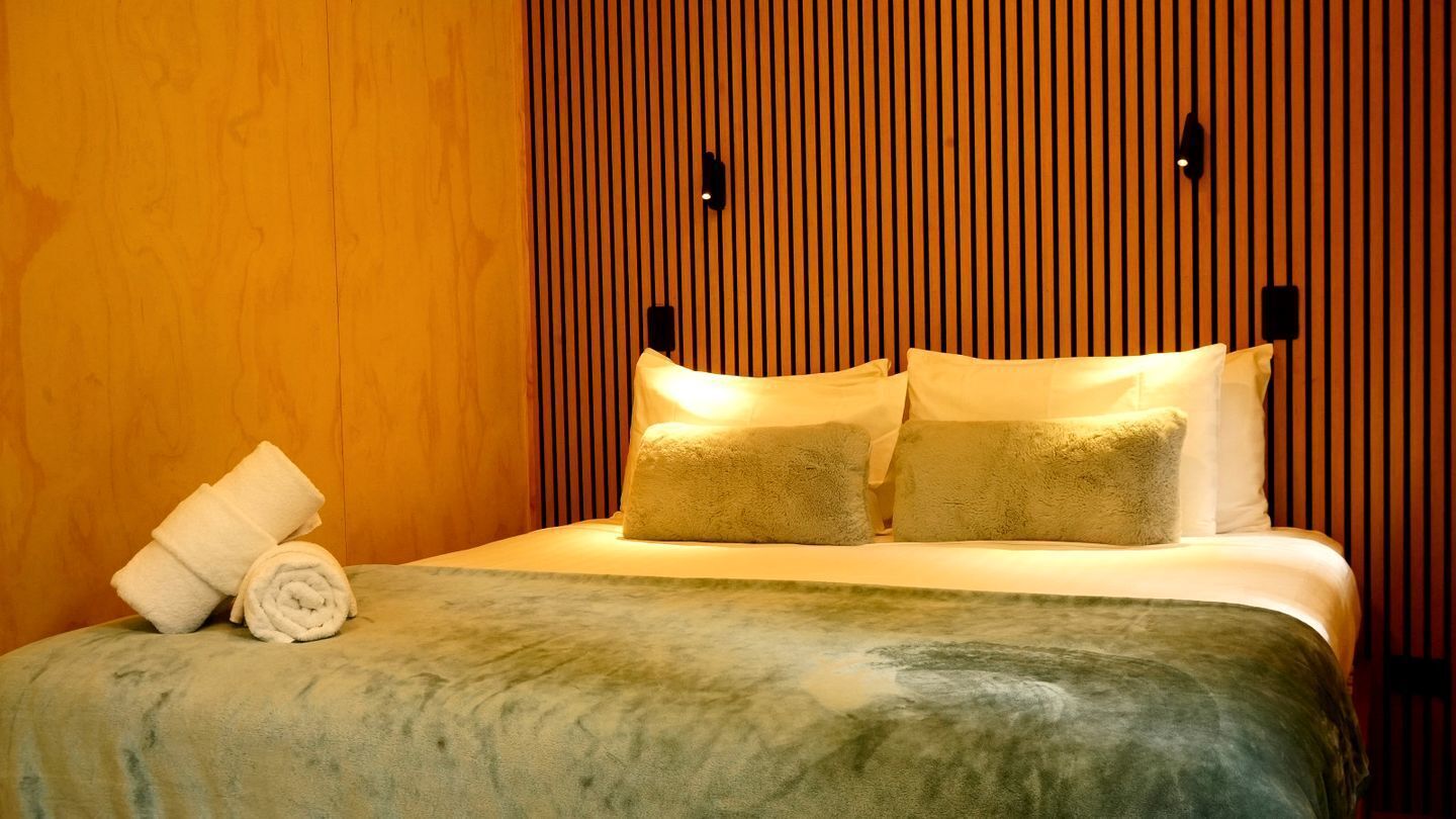 Une chambre d’hôtel avec un mur lambrissé en bois, un lit avec une literie blanche et deux oreillers.