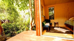 A wooden interior with a bed, a small table, and a bench.
