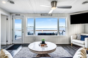 A room with a view of the water, a ceiling fan, a sign reading 'Lake Erie', and a couch.