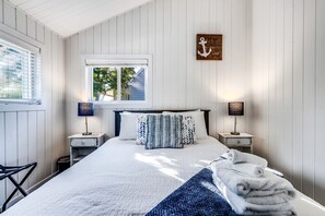 A bedroom with a bed, two bedside tables, a window, and a wall-mounted artwork. - Sweet Beach Rental with Jacuzzi, Deck and Amazing Sunsets in Ontario (Leamington)