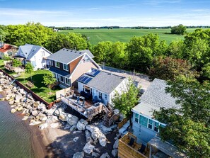 A residential area with houses, a dock, and a large green field in the background. - Sweet Beach Rental with Jacuzzi, Deck and Amazing Sunsets in Ontario (Leamington)