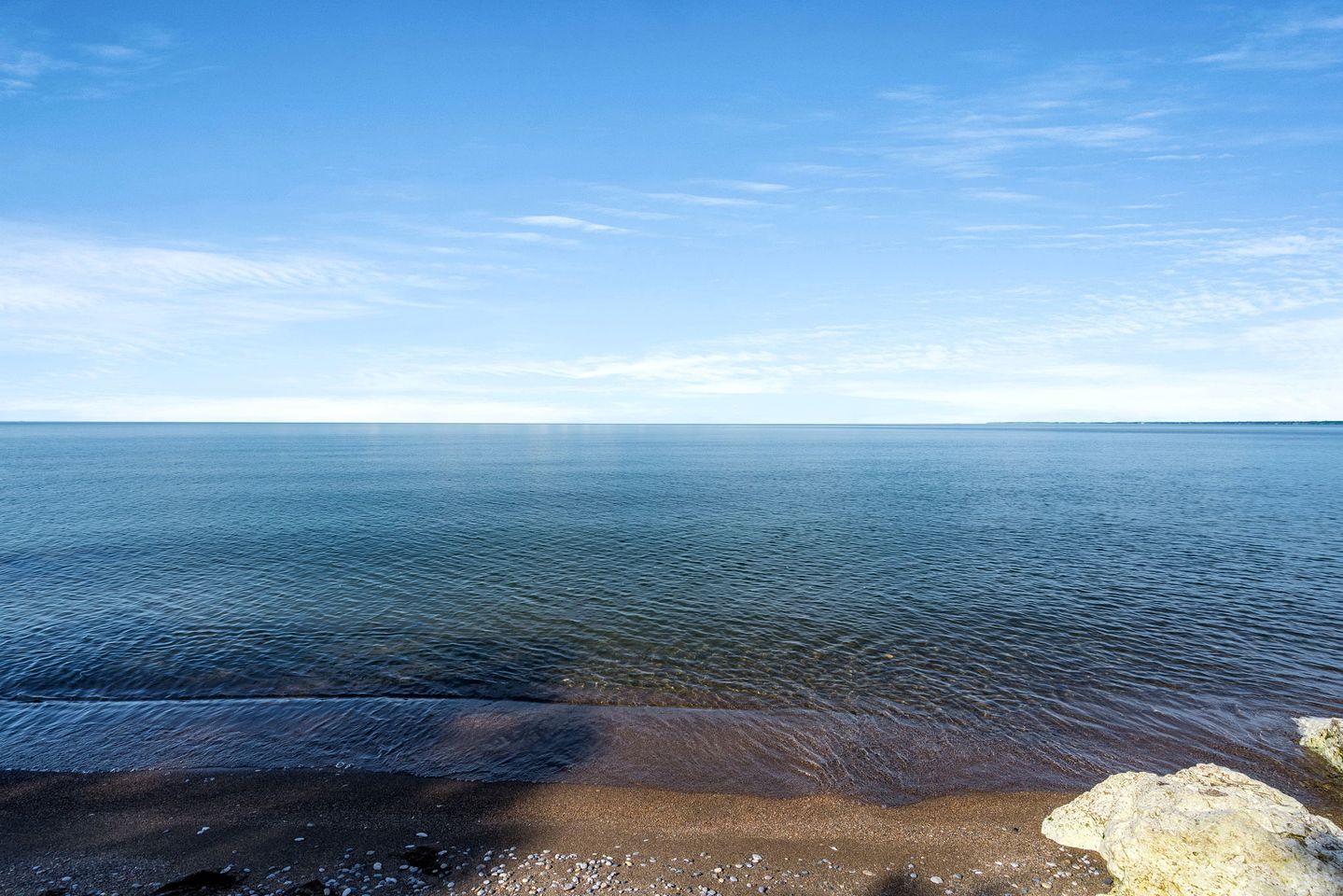 Une plage à l’eau claire, un rivage rocheux et un horizon lointain.