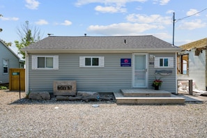A single-story building with a front door, two windows, a small porch, and a gravel driveway. - Sweet Beach Rental with Jacuzzi, Deck and Amazing Sunsets in Ontario (Leamington)