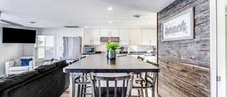 Una cocina moderna con una isla central, taburetes de bar y una pared decorativa de madera.