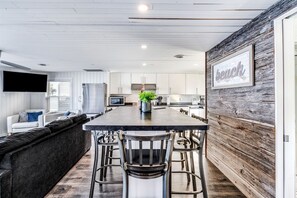 A modern kitchen with a central island, bar stools, and a wooden accent wall.