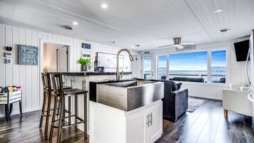 Une cuisine moderne avec un coin bar, des meubles blancs et une vue sur la plage.