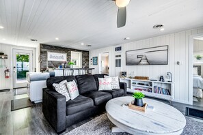 A modern living room with a black leather sofa, a round coffee table, and a mounted TV.