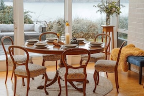 A dining area with a round table, six chairs, and a view of a lake.