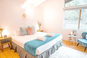 A bedroom with a bed, bedside tables, a chair, a window, and a view of trees.