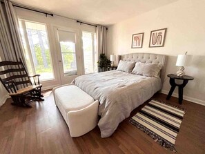 Ein Schlafzimmer mit Bett, Bank, Stuhl, Nachttischen und Bildern an der Wand.
