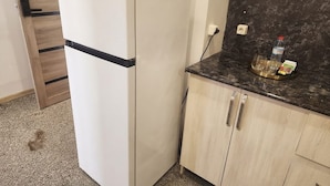 A compact kitchen with a white refrigerator, wooden cabinets, and a marble countertop. - Amazon Hotel - Full Board, Breakfast, Lunch & Dinner Included (Baku)