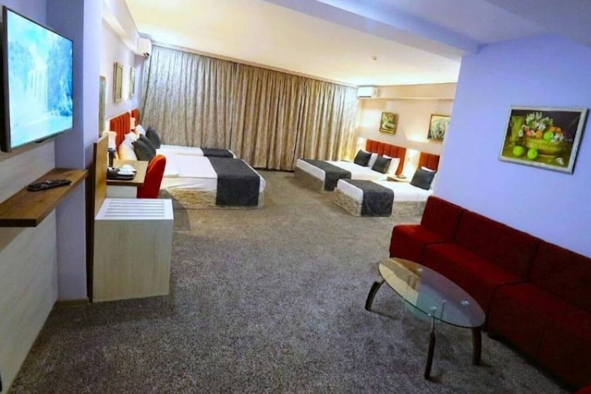Una habitación de hotel con una cama, dos sofás, un televisor y un escritorio.