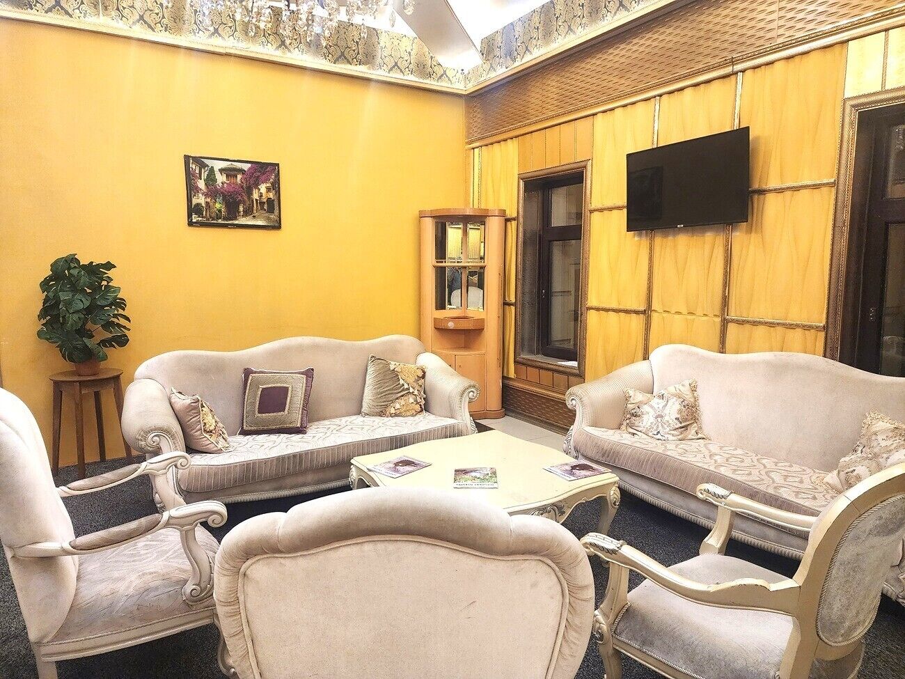 A room with a sofa set, a small table, a television, and a fireplace.
