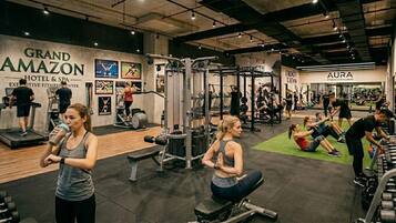 A gym with various exercise equipment, a treadmill, and people working out.