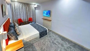 A hotel room with a bed, a TV, a desk, and a chair. - Amazon Hotel - Full Board, Breakfast, Lunch & Dinner Included (Baku)