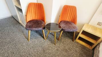 Twee stoelen en een ronde tafel in een hoek van een kamer met een vloerkleed.