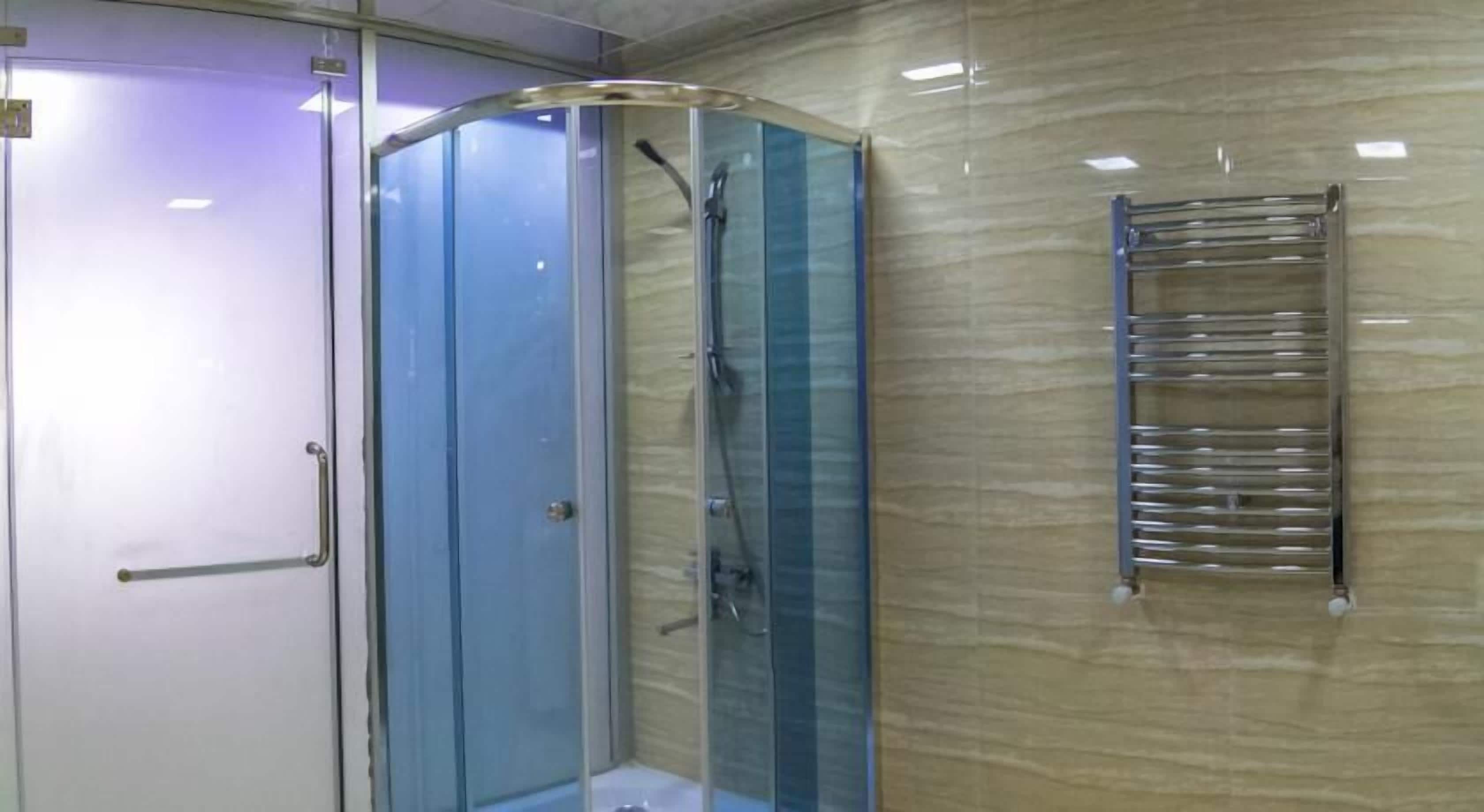 Casa de banho com chuveiro em cabine de vidro, porta-toalhas e porta com puxador.