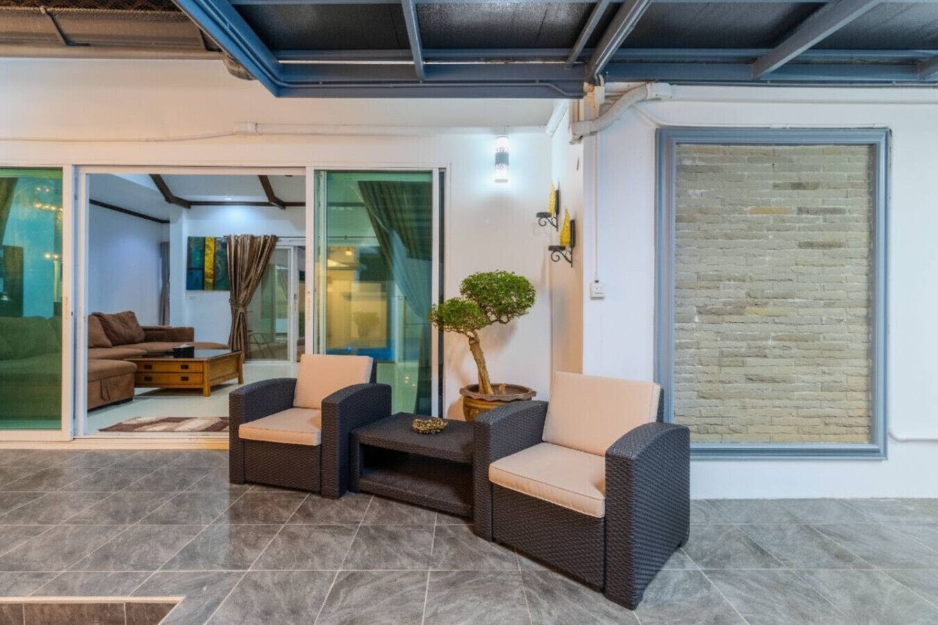 A modern living room with a glass door leading to a balcony, a potted plant, and a sofa.