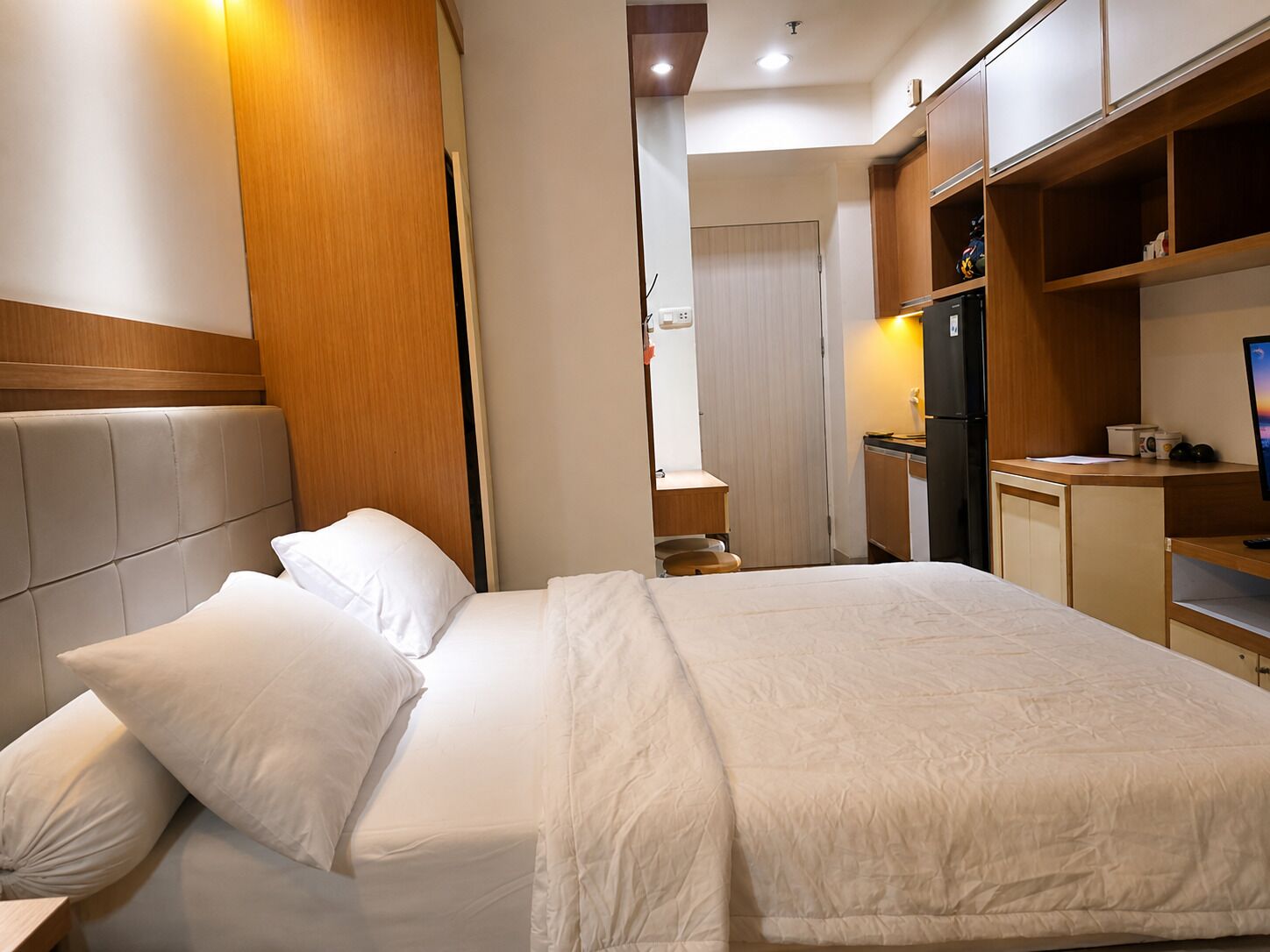 A hotel room with a bed, a desk, a computer, and a television.