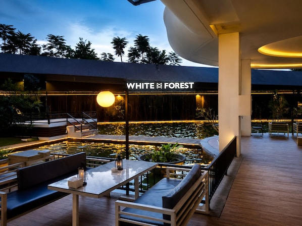 Moderni ulkoalue, jossa on uima-allas, penkkejä ja kyltti, jossa lukee ”WHITE FOREST”.