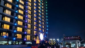 Un edificio de gran altura con varios pisos, ventanas iluminadas y un letrero llamativo con la palabra 'BEKASI' en la base.