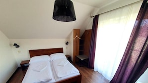 A bedroom with a wooden bed, a hanging wardrobe, and a bedside table. - Penzion U Adama (Dolná Tižina)