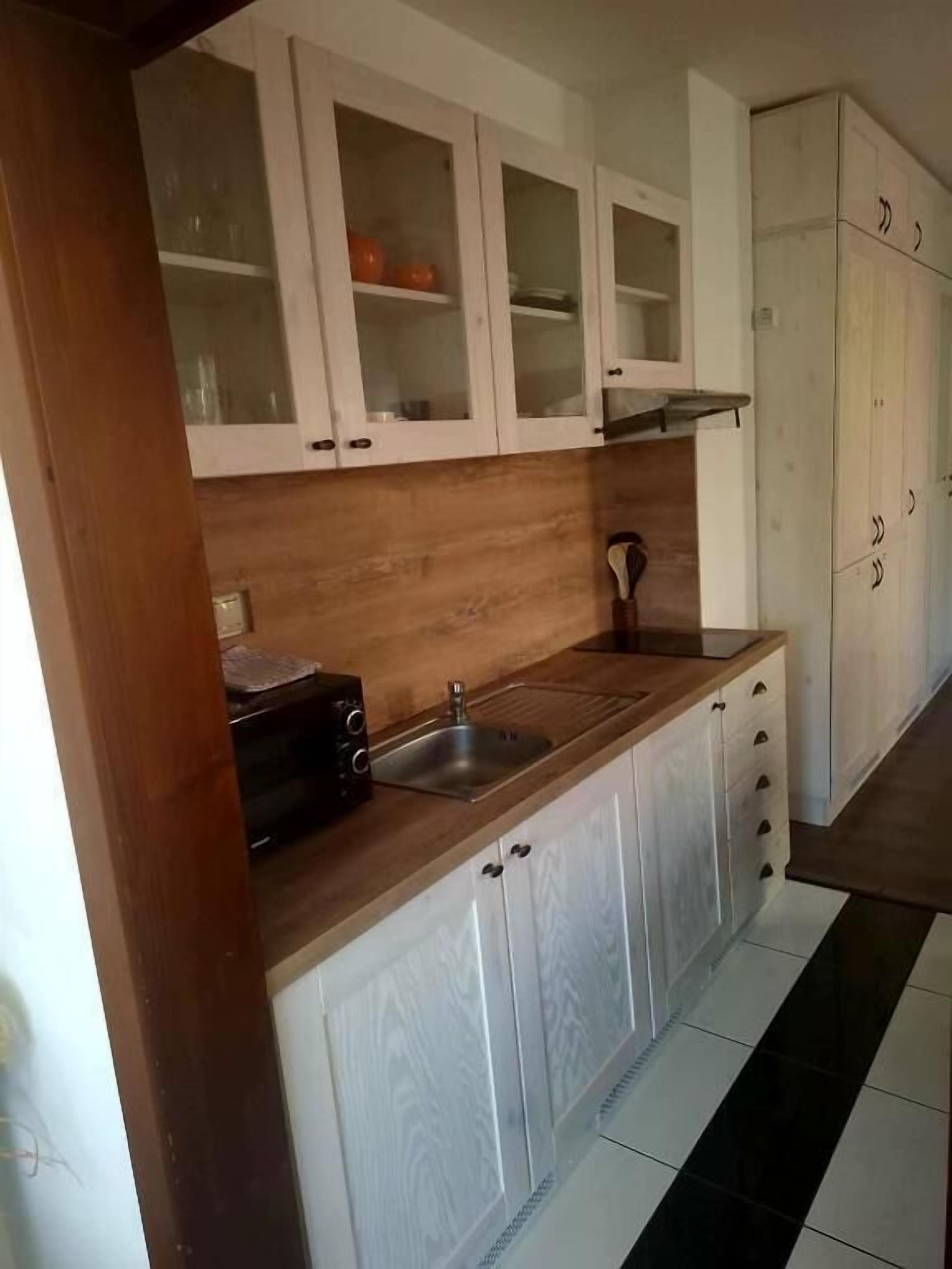 A kitchen with white cabinets, a wooden countertop, and a black toaster.