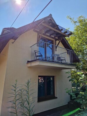 A two-story building with a balcony, a window, and a door.