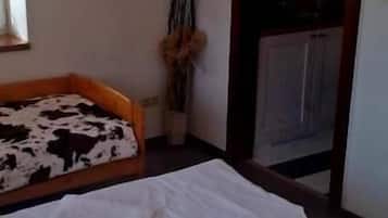 Una habitación con una cama, una mesita con un florero y una puerta que da a una cocina.