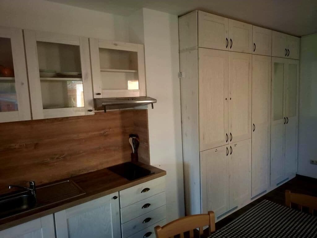 Una cocina con encimeras de madera, un fregadero y armarios blancos.
