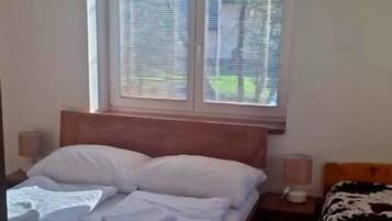 A bedroom with a bed, bedside table, and a window with blinds.