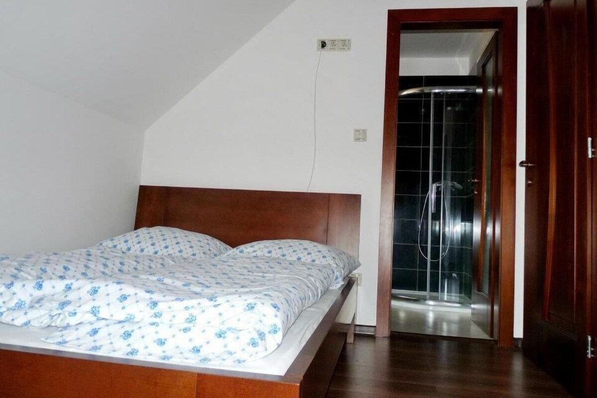 Un dormitorio con una cama de madera, una ducha y una puerta que da a otra habitación.
