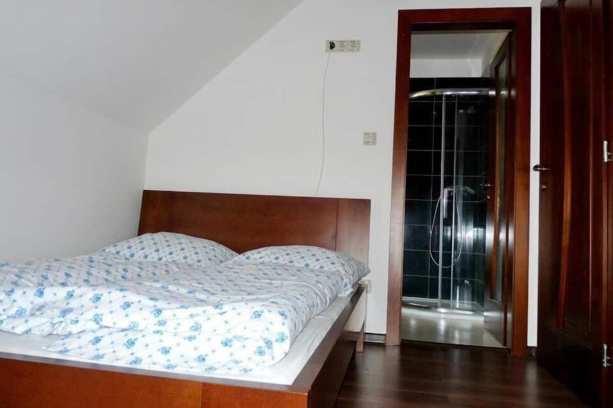 Une chambre Ă coucher avec un lit en bois, une douche et une porte donnant sur une autre piĂšce.