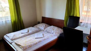 A double bed with a wooden headboard, a small bedside table, and a chair.