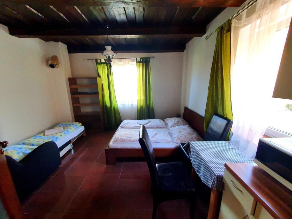 A small room with two beds, a desk, a chair, and a TV.