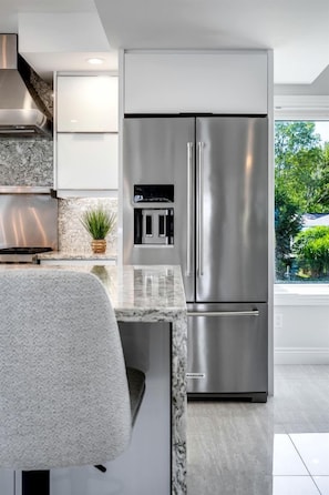 A modern kitchen with a stainless steel refrigerator, a built-in oven, and a marble countertop. - Luxury Waterfront Estate with Beach Access and Expansive Grounds in Ontario, Canada (Wheatley)