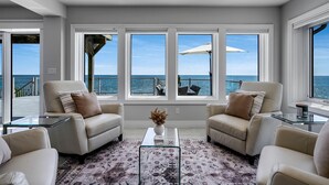 Un soggiorno moderno con vista sull'oceano, caratterizzato da due poltrone, un tavolino in vetro e un tappeto decorato.
