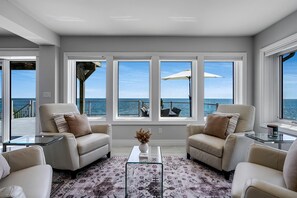 A modern living room with a view of the ocean, featuring two armchairs, a glass coffee table, and a patterned rug. - Luxury Waterfront Estate with Beach Access and Expansive Grounds in Ontario, Canada (Wheatley)