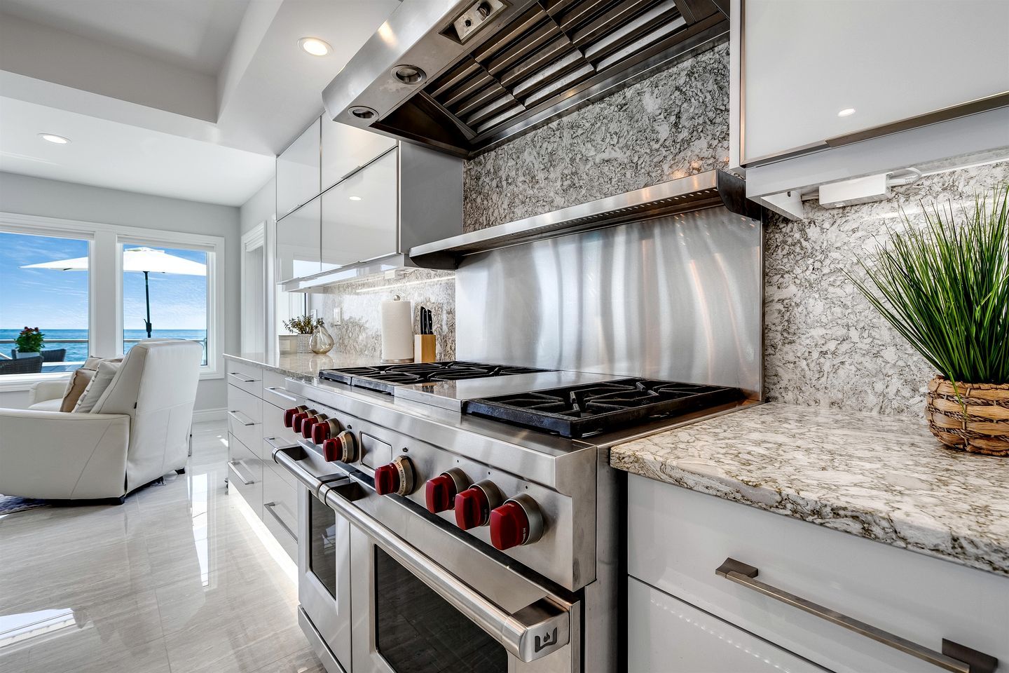 A modern kitchen with a stove, oven, and marble countertop.