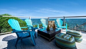 Una terrazza con poltrone Adirondack blu, un tavolo con piano in vetro e pouf decorati.